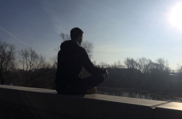 Miracle Morning - junger Mann meditiert bei Morgenroutine zum Sonnenaufgang