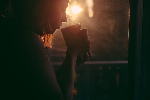 Junge Frau trinkt grünen Tee zu Sonnenaufgang